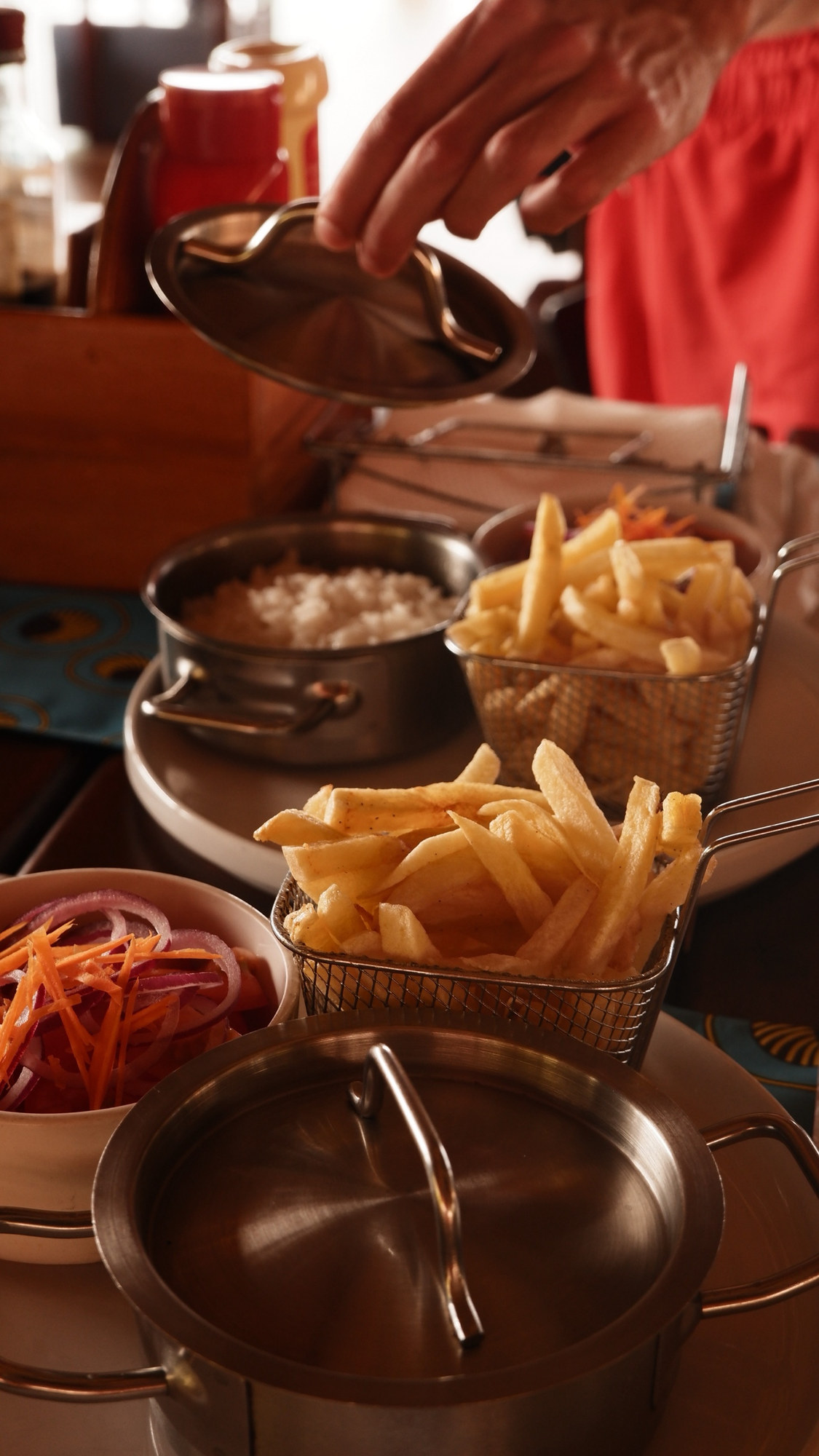 Fries in wire baskets with a lid being lifted