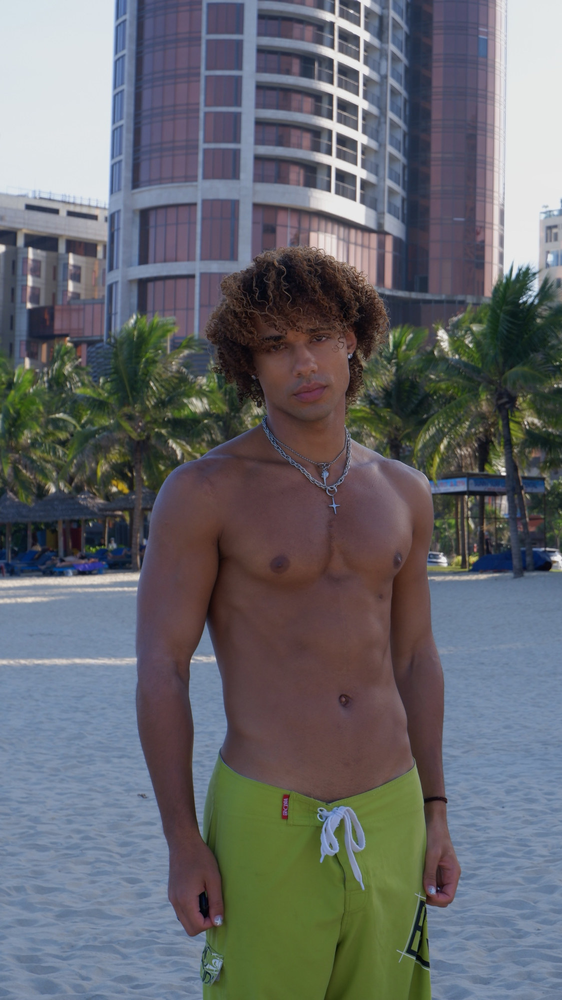 João on the beach in green board shorts