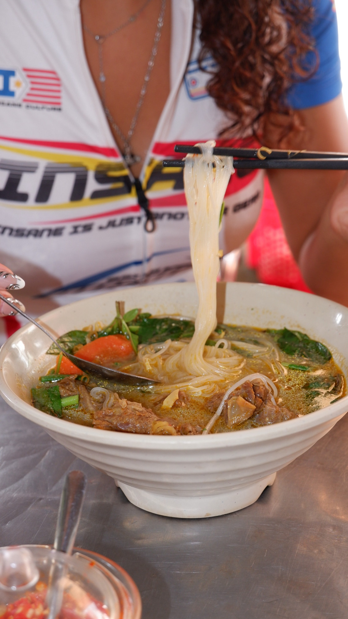 Noodles lifted with chopsticks from a bowl of beef soup
