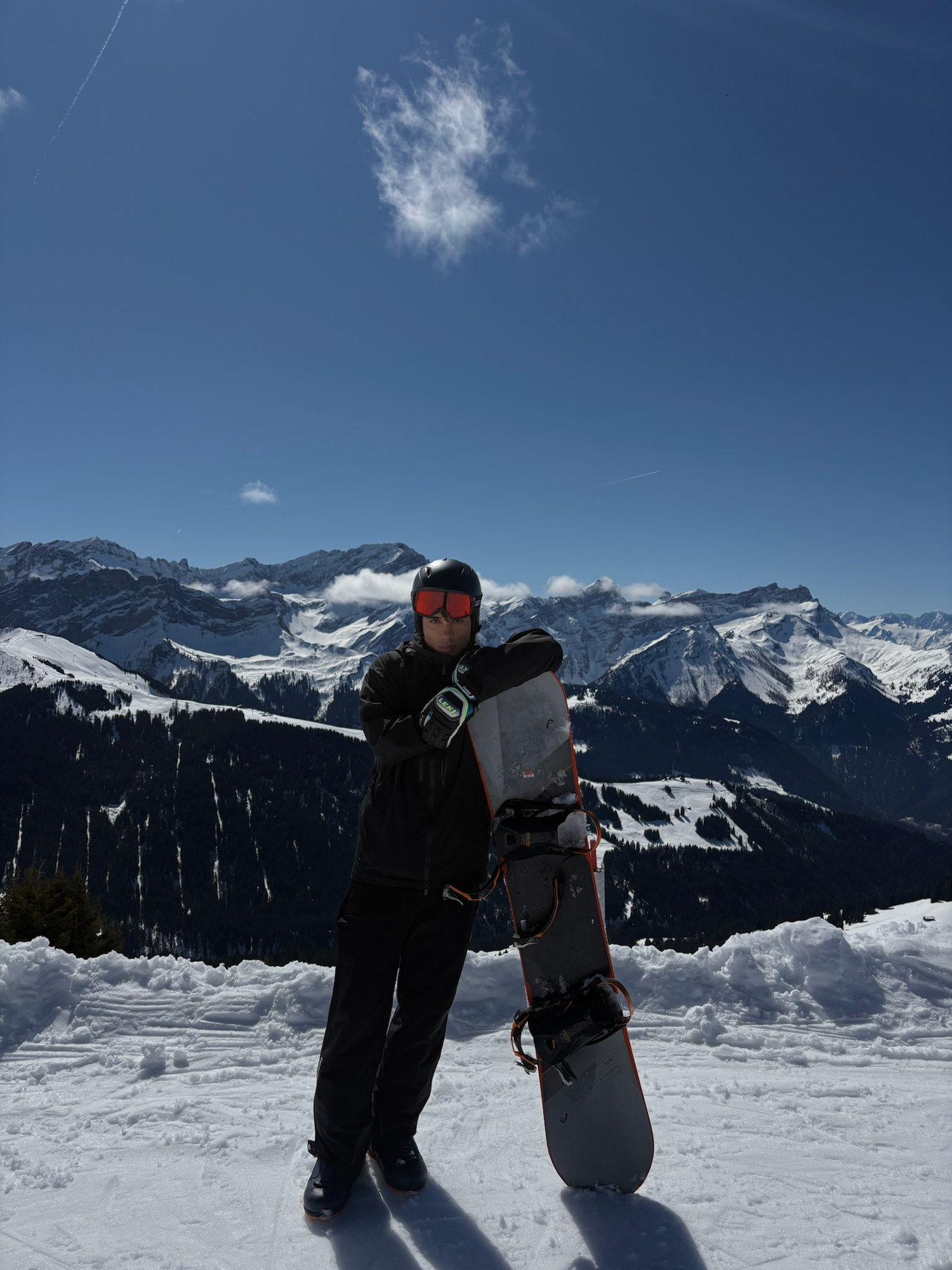 João with a snowboard in front of snowy mountains