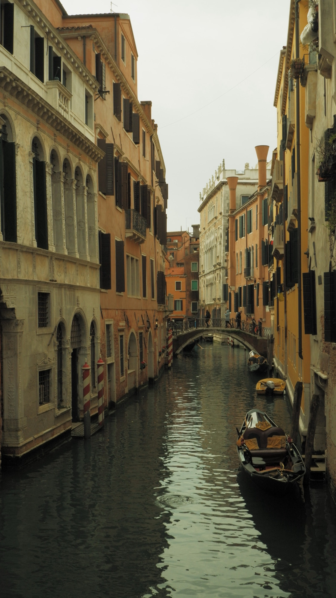 A narrow canal between orange houses with a gondola moored