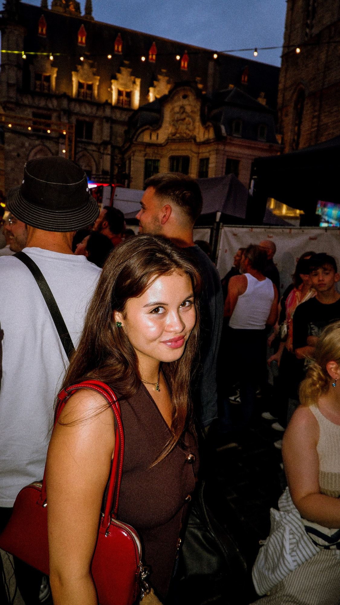 A young woman smiling over her shoulder at an evening street festival
